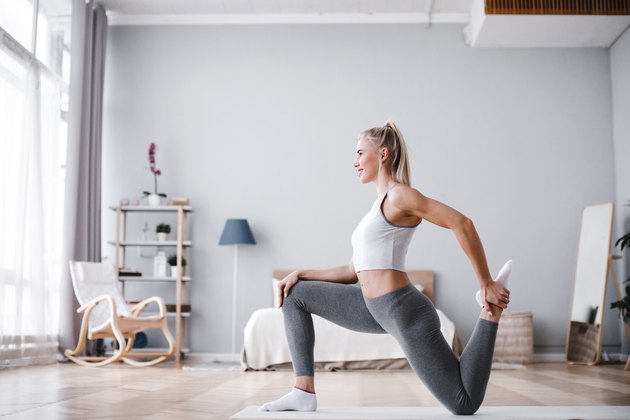 Sporty beautiful woman stretching exercising at home.