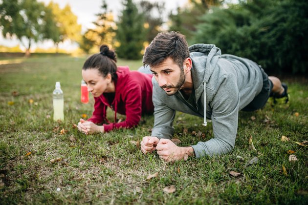 Man and woman doing forearm planks and squeezing their glutes for stronger plank form