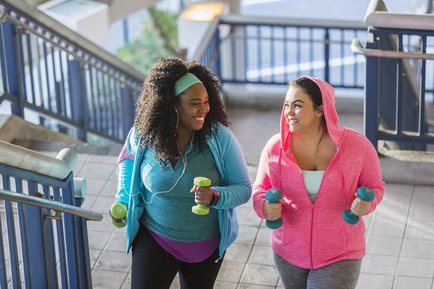 Two young women exercising, powerwalking up stairs