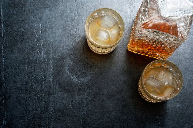 Glasses of bourbon with ice cubes on stone table. Top view