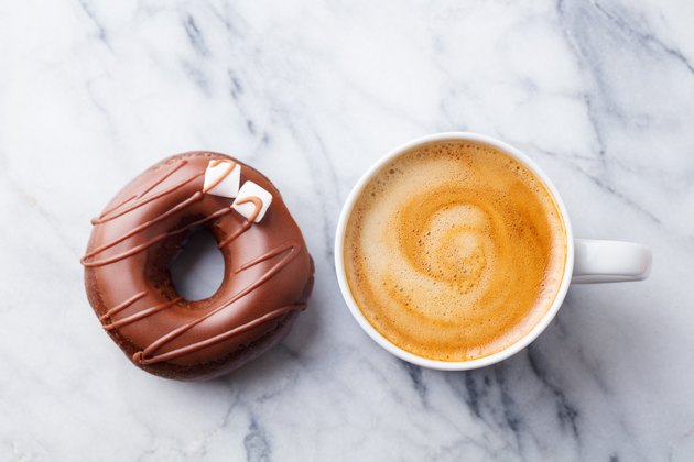 Coffee with chocolate donut in marble table background. Top view.