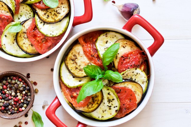 Baked nightshade vegetables with olive oil and spices on white table.