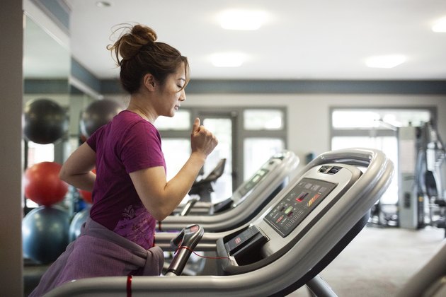 Side view of woman exercising on treadmill at gym