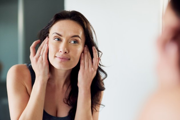 A woman looking at her face in the mirror