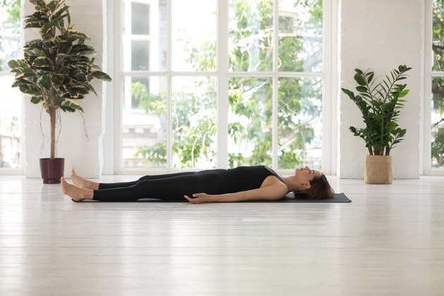 Woman demonstrating how to do the yoga pose Corpse Pose (Savasana)