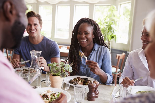 Group Of Friends Sitting At Table In Restaurant Enjoying Meal Together