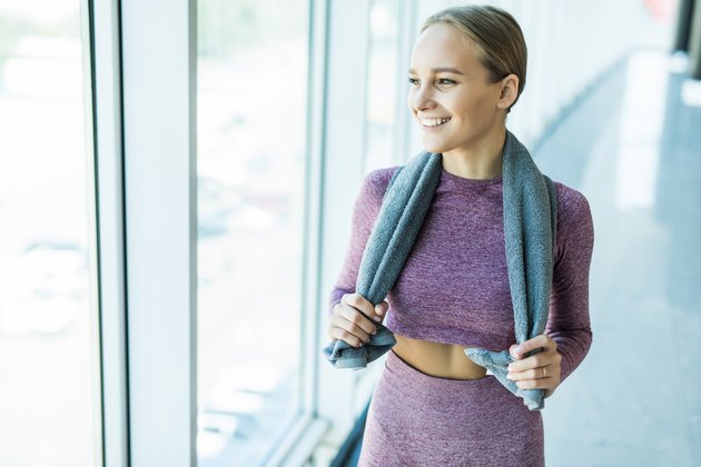Fitness woman rest after workout in gym with towel around her neck
