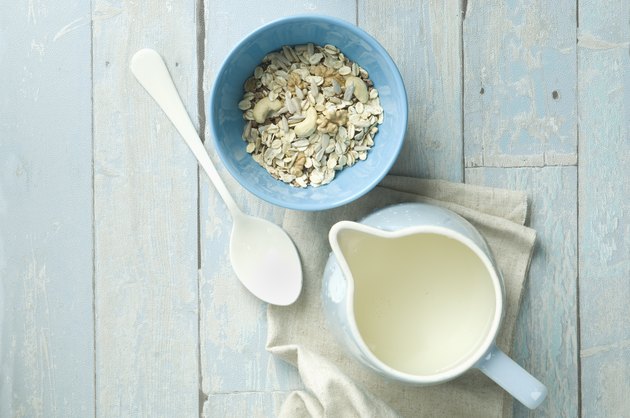 Bowl of granola with walnuts, cashew nuts, sunflower seed and a milk jug