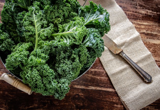 Kale in basket and knife on wooden background top view on daylight superfood vegetables