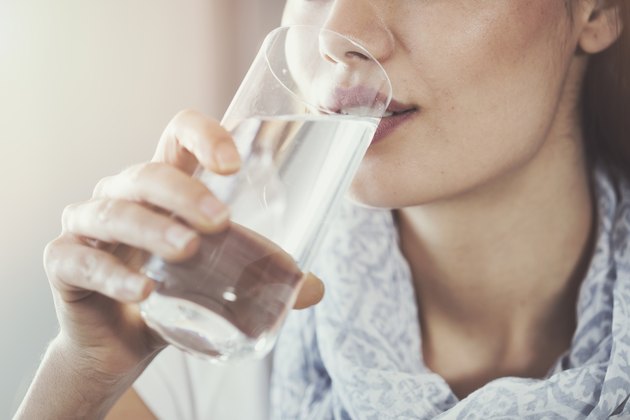 Eine Frau, die Wasser als natürliches Heilmittel gegen Verstopfung trinkt