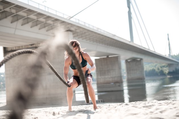 Women athlete doing workout with battle rope
