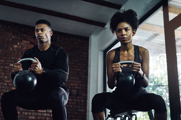 man and woman holding kettlebells doing muscle-building goblet squats