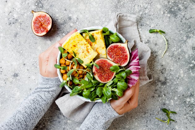 Vegan, detox Buddha bowl recipe with plant-based protein foods and turmeric roasted tofu, figs, chickpeas and greens. Top view, flat lay
