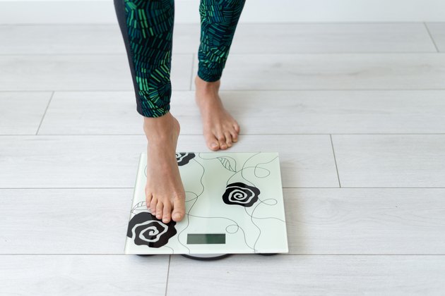 A woman in colorful leggings stepping onto a bathroom scale decorated with flowers