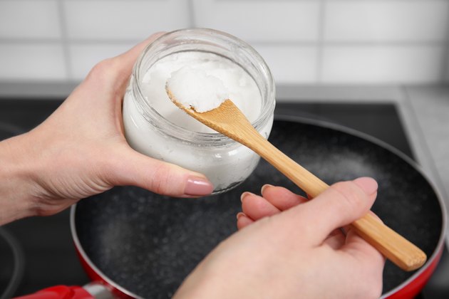 Woman putting coconut oil into frying pan