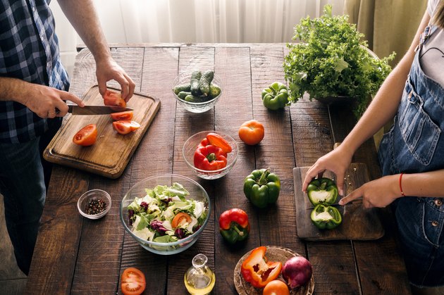Married couple cooking together dinner vegetables salad in home kitchen, top view