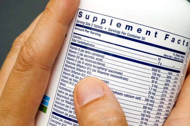 White plastic jar with supplement facts of multivitamins in woman hands.