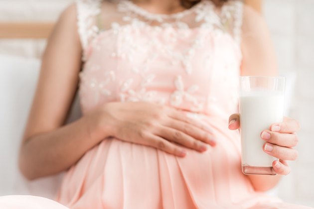 Midsection Of Pregnant Woman Holding Milk Glass