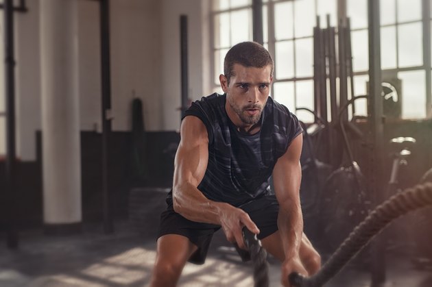 男人在健身房使用战斗绳索来锻炼肌肉