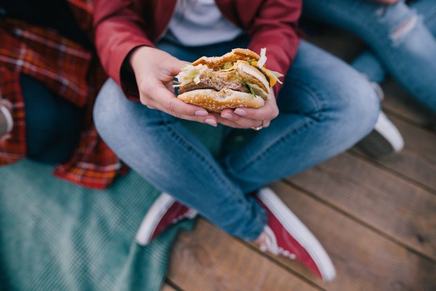 女人的手中的鲜美汉堡。外卖垃圾食品