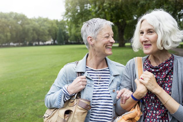 Two older women walking and laughing together in a park