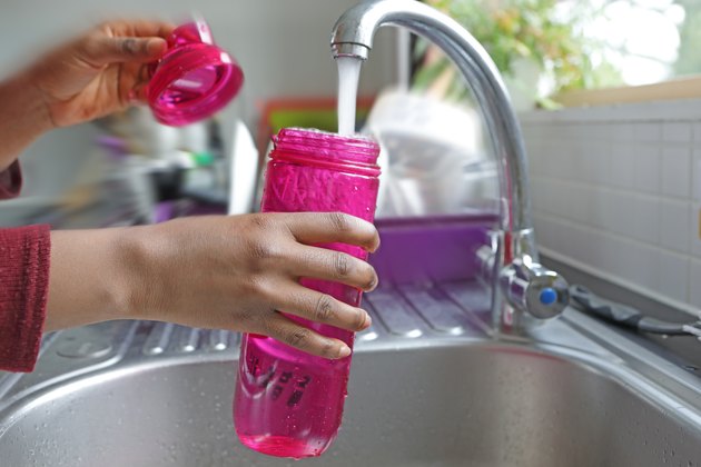 Detail of hands filling water bottle at a sink