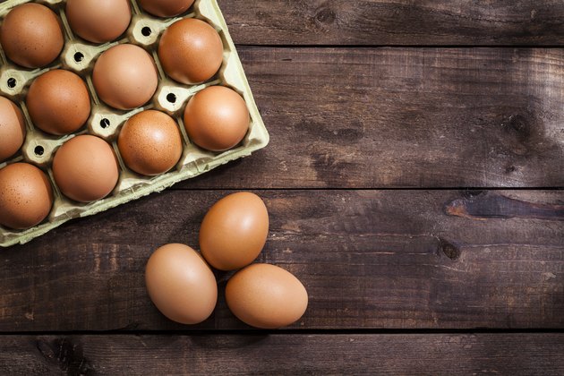 Eggs in a cardboard carton on a wooden table