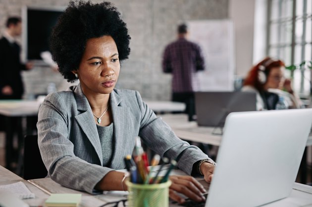 African American businesswoman typing an e-mail on laptop at work.
