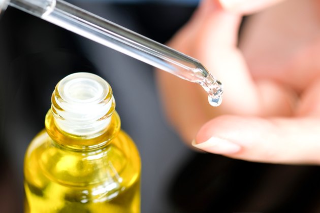 hands of a beautiful woman Dropping serum collagen moisturizer of face into clear yellow bottle soft light background. Protector skin Treatment facial essence oil, Vitamin C. Beauty and spa Concept