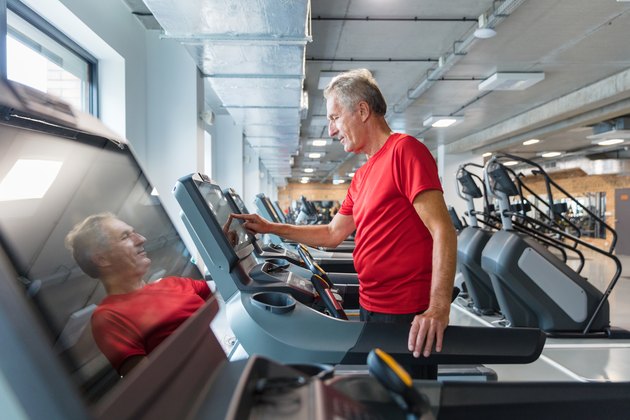Senior man adjusting speed on treadmill, walking for an hour