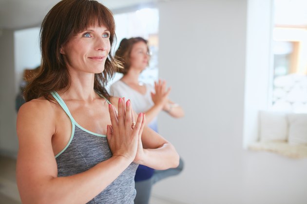 Female trainer with student doing Vrikshasana