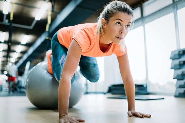 Young attractive woman doing push ups using ball