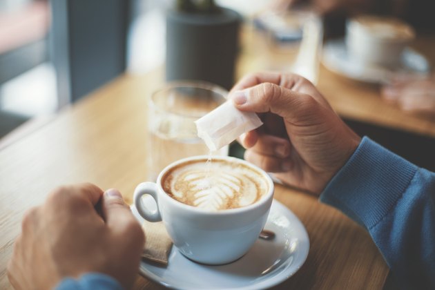 Young man with sensitive stomach puting sugar in his coffee