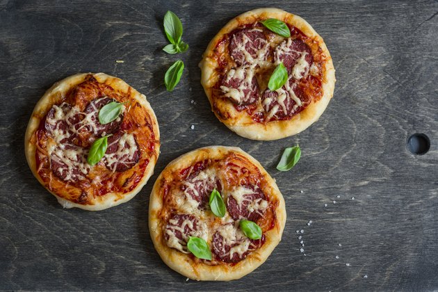 Mini salami pizza on a dark wooden background, top view