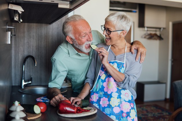 senior woman feeding senior man a slice of cucumber