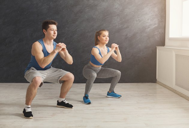Young couple in sportswear doing squat