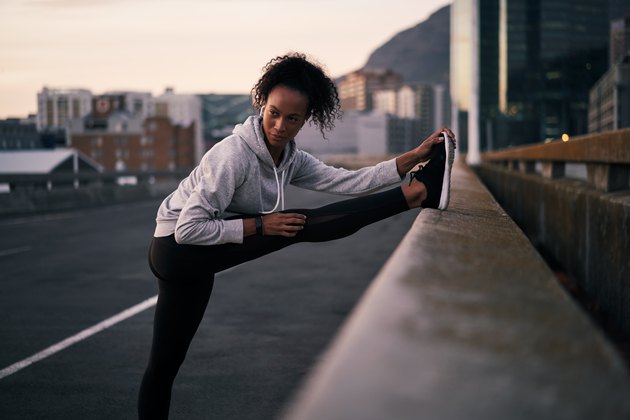 Woman stretching during run in urban area