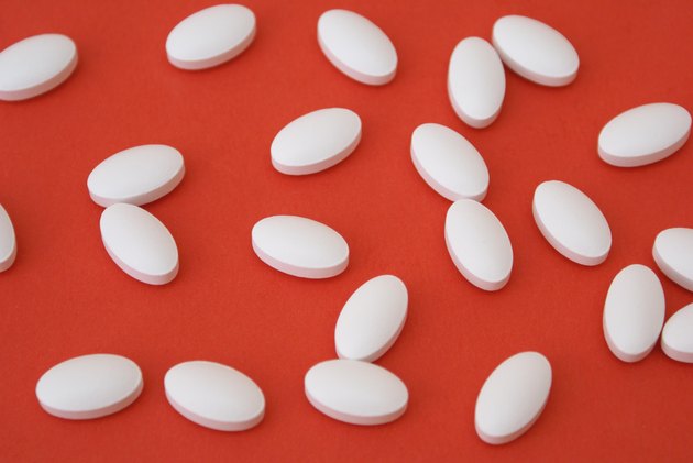 White oval IP 466 ibuprofen pills on a red background