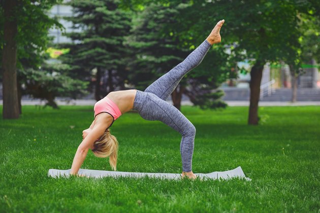 Young woman making wheel pose outdoors