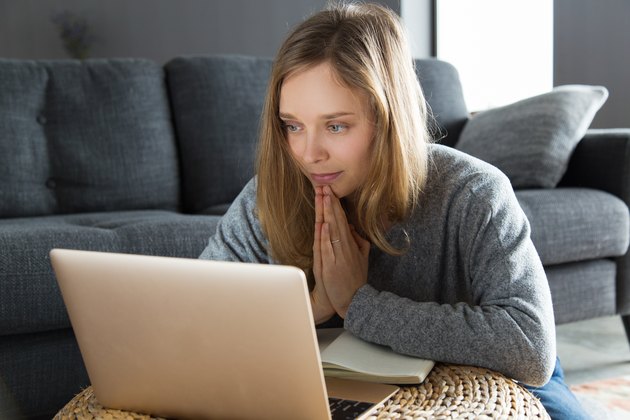 young woman having video teletherapy on laptop next to couch