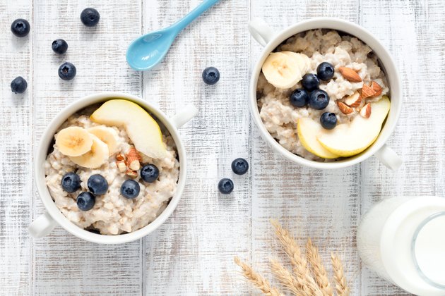 Oatmeal porridge in bowl on white table top view
