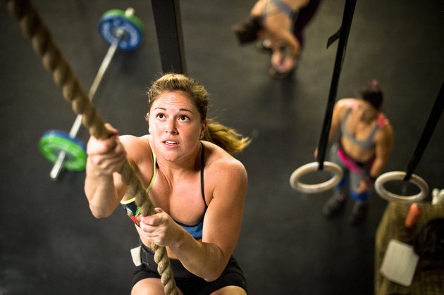 女运动员进行爬绳在CrossFit健身房