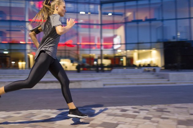 Woman listening to music and running in Dusk