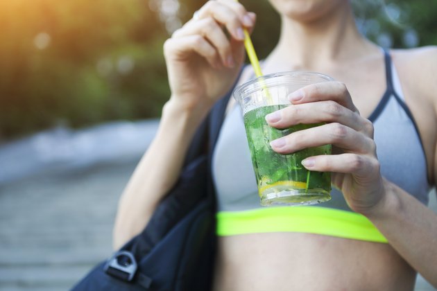 Woman drinking herbal tisane after fitness running workout on summer day
