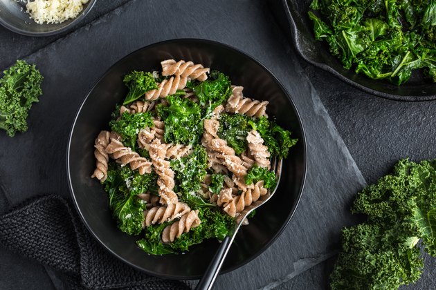 Whole grain pasta with kale in black bowl