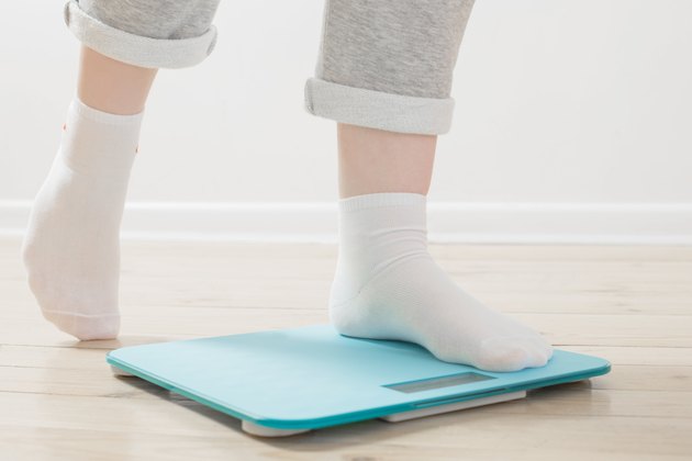 female legs on electronic scales on wooden floor