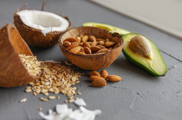 Healthy food concept with avocado, cocos, almonds and oatmeal over gray background near window.