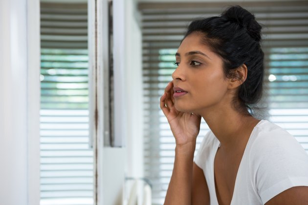 Woman touching face in bathroom