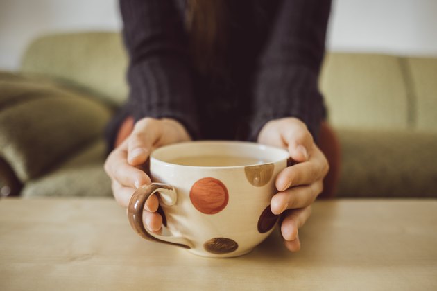 Womans hands holding tea cup, close-up
