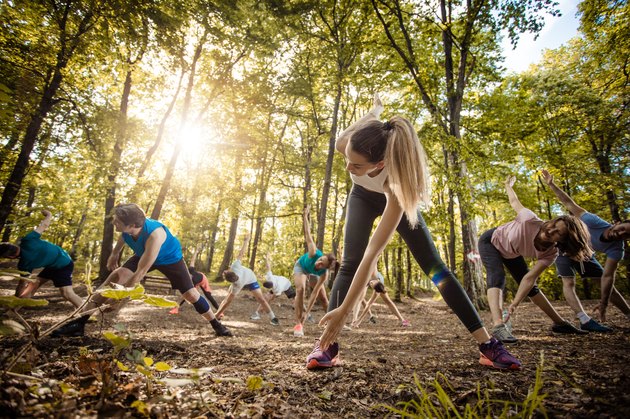 Large group of athletes warming up before sports training in the park.